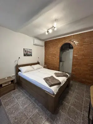 a bedroom with a large bed and a brick wall at 3D Studio in Varna City