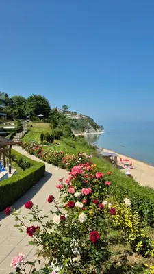 a garden with red and white flowers next to a beach at White Cliffs первая линия in Byala