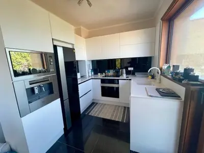 a kitchen with white cabinets and a large window at First Line Lozenez Beach Anron in Lozenets