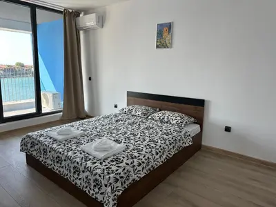 a bedroom with a bed and a large window at Sozopol Beach Apartments in Sozopol