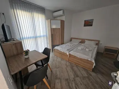 a small room with a bed and a table and a desk at Студио Морелия in Tsarevo