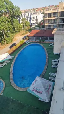 a large swimming pool with lawn chairs and an umbrella at One bedroom studio in Chernomorets