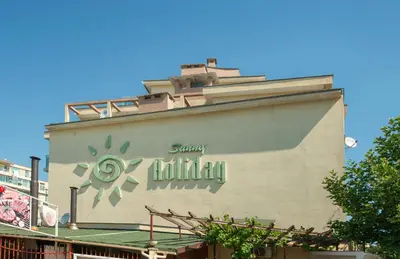 a building with a sign on the side of it at Sunny Holiday Apartments in Sunny Beach