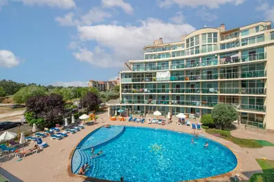 a hotel with a swimming pool and a large building at Sunny Holiday Apartments in Sunny Beach
