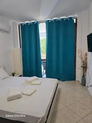 a bedroom with a bed with blue curtains and a television at Elia Relax & Lux in Aheloy