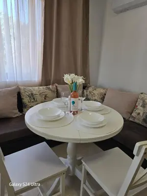 a white table with plates and glasses and a couch at Elia Relax & Lux in Aheloy