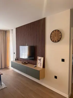 a living room with a television and a clock on the wall at South Beach Apartment Primorsko 2 in Primorsko