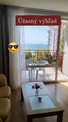 a living room with a table and a view of a balcony at Grand rezort Marína Beach in Sveti Vlas