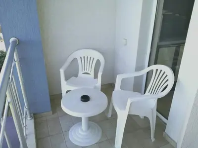 two white chairs and a table on a balcony at Apartment Stoyanovi in Primorsko
