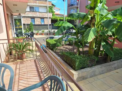 a balcony with a bench and some plants and a building at Къща за гости Авеню in Ravda