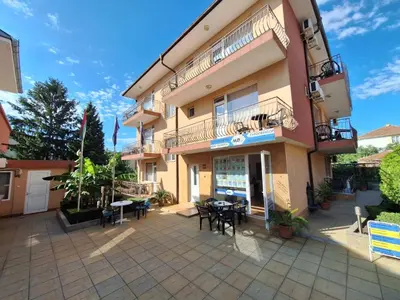 a building with a patio with tables and chairs at Къща за гости Авеню in Ravda