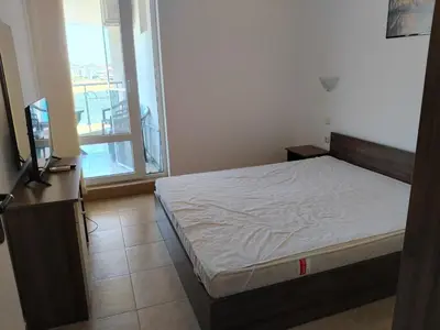 a bedroom with a bed and a television and a balcony at 2 Room Apartment Costa Calma Aheloy Bulgarien in Aheloy