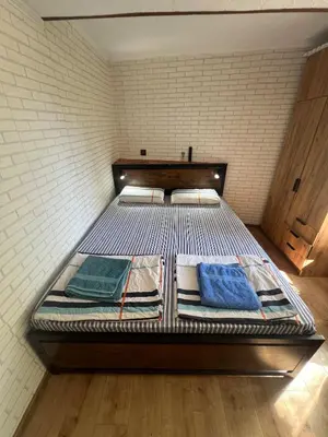 a large metal bed in a room with a brick wall at Studio Vili 2 in Varna City