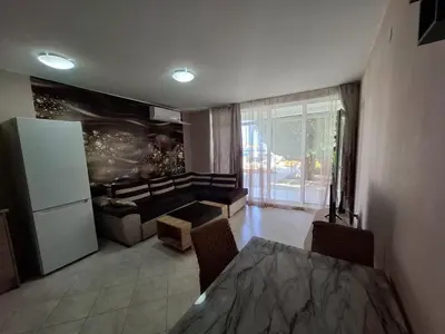 a living room with a table and a refrigerator at Sunset Complex Кошарица Апартамент 15 in Kosharitsa
