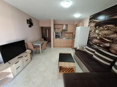 a living room with a couch and a television at Sunset Complex Кошарица Апартамент 15 in Kosharitsa