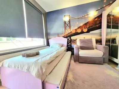 a bedroom with a bed and a chair and a window at Aquapark 2BD Apartment for Family in Sunny Beach