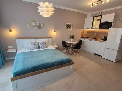 a bedroom with a large bed and a kitchen at Verano Deluxe Studios in Burgas City
