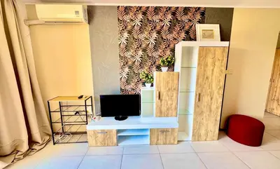 a living room with a tv on a table with a tv at Apartcomplex Grand Kamelia Sunny Beach in Sunny Beach