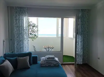 a living room with a blue couch and a window at Sunrise home in Burgas City