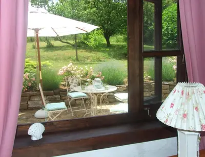 a window view of a patio with a table and an umbrella at Bulgarian country house near the sea in Banya