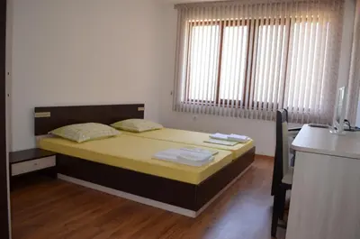 a bedroom with a bed and a desk in it at Guest House Georgievi in Primorsko