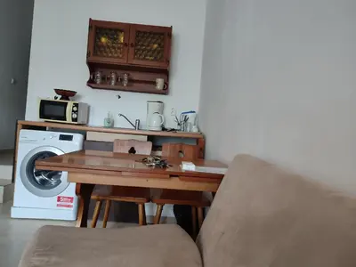 a living room with a table and a washing machine at Партерни студия без обособен балкон ул Т Светослав 5 и ул България in Pomorie