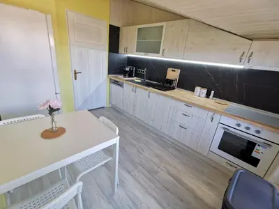 a kitchen with a white table and a black wall at Апартамент Хармония ТОП Център в Стария Град in Pomorie