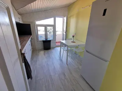 a kitchen with a white refrigerator and a table at Апартамент Хармония ТОП Център в Стария Град in Pomorie
