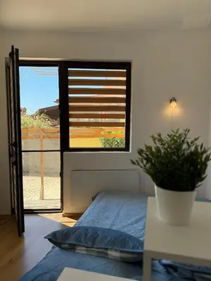 a bedroom with a bed and a window with a plant at Sarafovo Sea and Airport Stay in Burgas City