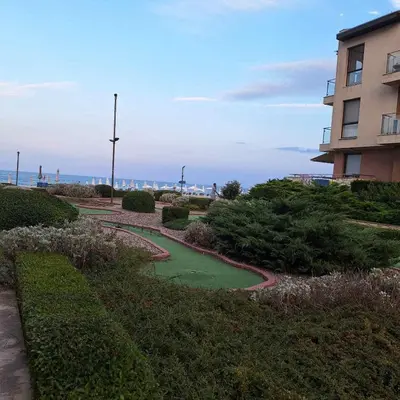 a garden with a green pond next to a building at Panoramic sea view at the beach in Obzor