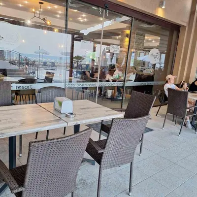 a table and chairs in a restaurant with people eating at Panoramic sea view at the beach in Obzor