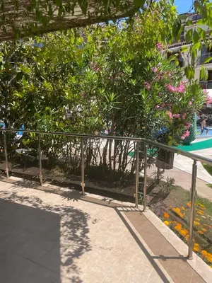 a metal fence next to a park with flowers at Family Paradise in Laguna Beach Hotel in Sozopol