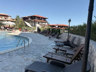 a row of wooden benches next to a swimming pool at Stylish studio near harbor and luxury beach in Sveti Vlas