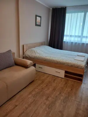 a bedroom with a bed and a couch and a window at Силви Съни Бийч Плаза in Sunny Beach