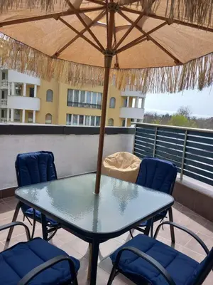 a table with chairs and an umbrella on a balcony at Силви Съни Бийч Плаза in Sunny Beach