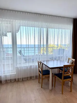 a dining room with a table and chairs and a large window at Byala sea view apartment Studio in Byala