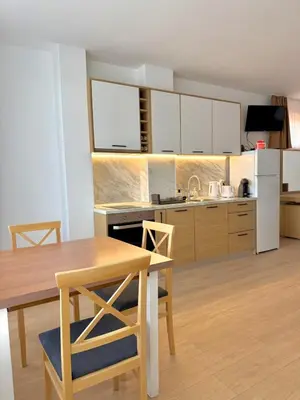 a kitchen with a wooden table and a kitchen with white appliances at Byala sea view apartment Studio in Byala