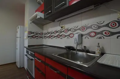 a kitchen with a stainless steel sink and red cabinets at Atlantic Complex Ravda in Ravda
