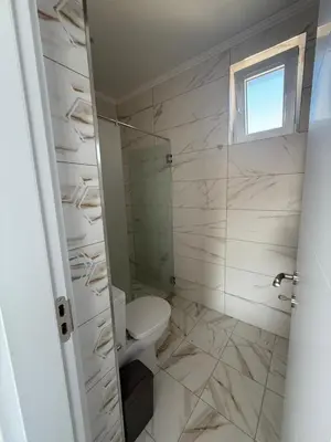 a white bathroom with a toilet and a window at Aurum Villas Smokinya Beach 4 in Sozopol