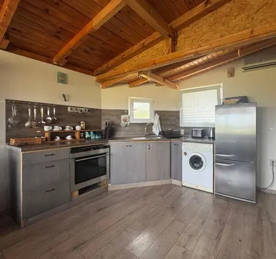 a kitchen with stainless steel appliances and a wooden ceiling at Къща за гости тип Бунгало Арапя, Царево in Tsarevo