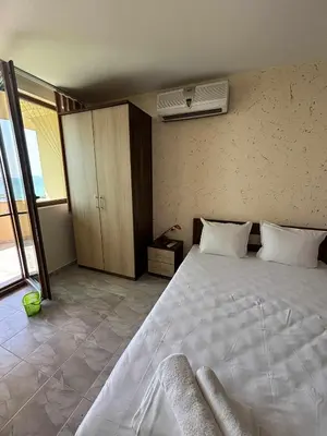 a bedroom with a large white bed and a window at Стаи за гости Денкови in Burgas City