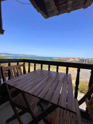 a wooden table on a balcony with a view of the ocean at Windmill Nessebar studio with sea view in Nesebar