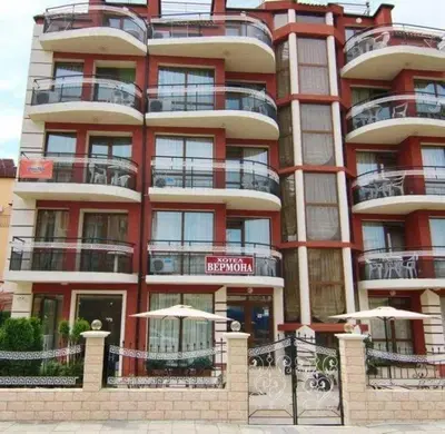 a tall red building with umbrellas in front of it at Семеен хотел Вермона in Primorsko