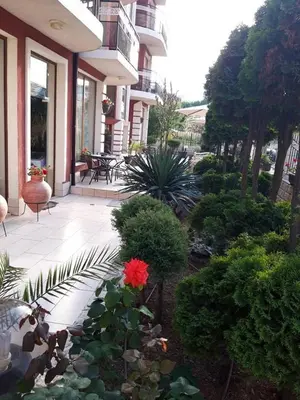 a house with a garden with a red flower at Семеен хотел Вермона in Primorsko
