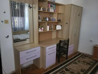 a wooden cabinet with a mirror and a chair in a room at Апартамент Стоянови in Primorsko