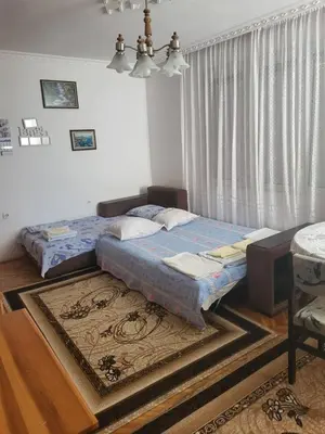 a bedroom with a bed and a window with a rug at Апартамент Стоянови in Primorsko