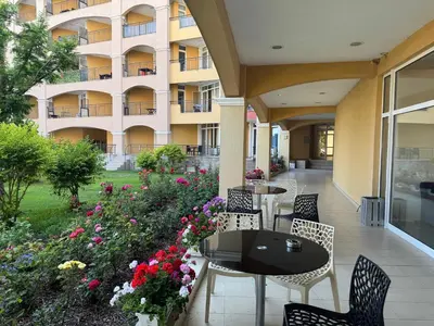 a patio with tables and chairs and flowers in front of a building at Black Sea Residence Aheloy in Aheloy