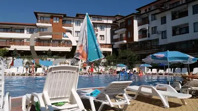 a group of chairs and umbrellas in a swimming pool at Gardenia Hills Studio in Sunny Beach
