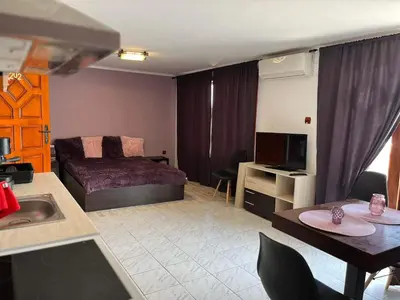 a living room with a bed and a kitchen with a table at Vila Nikoleta in Sveti Vlas
