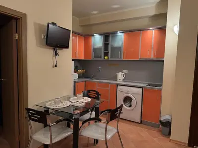a kitchen with a table and chairs and a kitchen with orange cabinets at Apartment 300m from private beach VILA ROMANA Royal Castle in Sveti Vlas